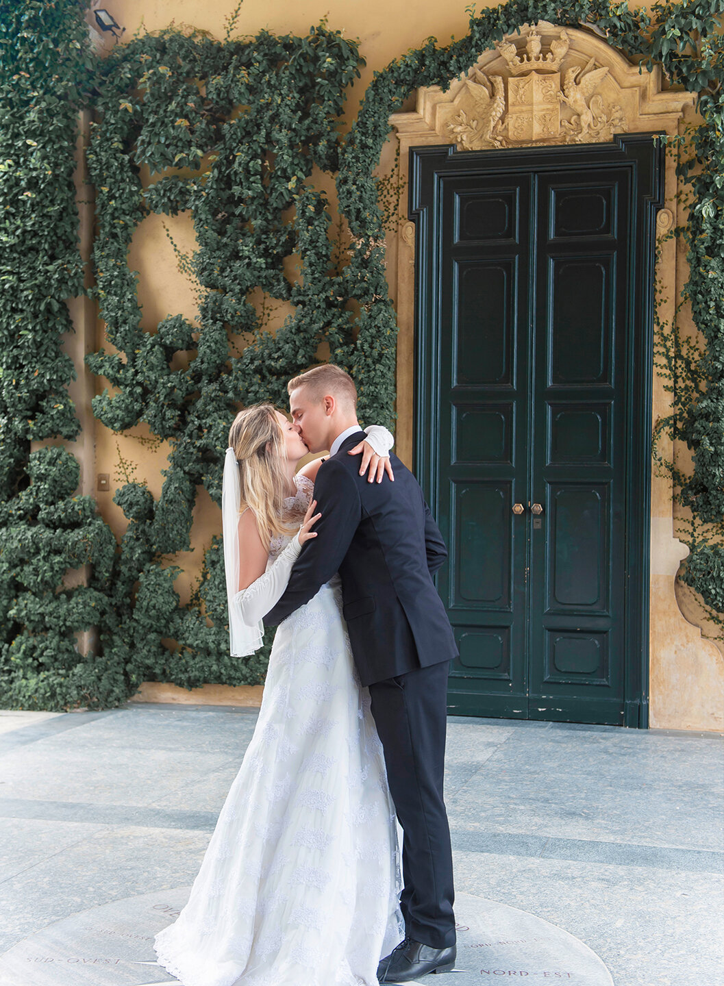 Andrea and Jo kissing in front of a flowery doorway